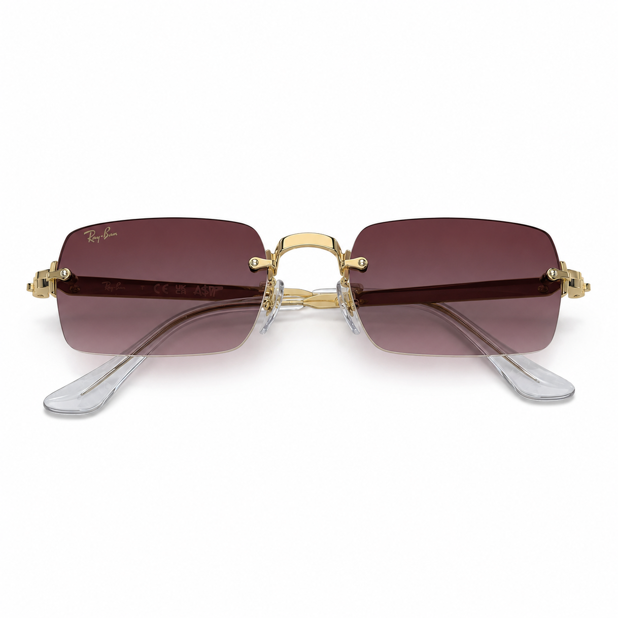 A bold rimless rectangular frame from the A$AP Rocky x Ray-Ban collection, featuring burgundy gradient lenses, polished gold-tone metal details and transparent temple tips.
